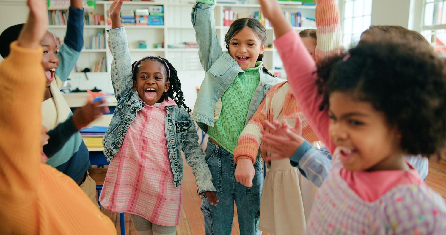 100 Gründe für Tanz in der Schule – GS, Sek 1 & Sek 2 Eine Gruppe von glücklichen Schulkindern jubelt und tanzt gemeinsam im Klassenzimmer – Tanz als holistisches Bildungswerkzeug.