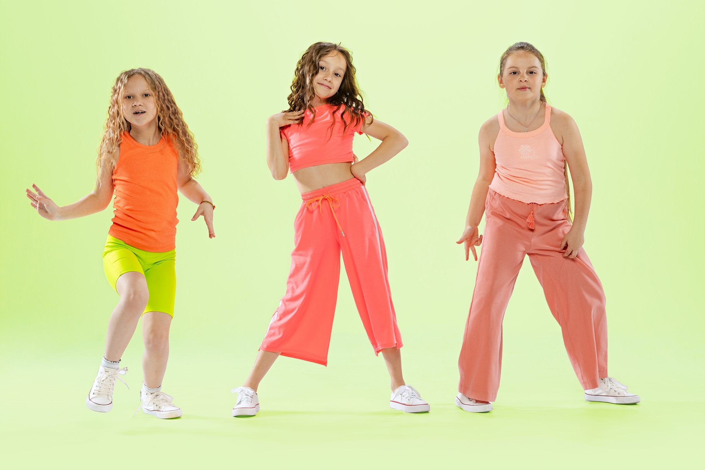Tanz im Unterricht: Mut machen mit groove2grow Drei selbstbewusste Mädchen in sportlicher Kleidung tanzen und posieren vor grünem Hintergrund – Tanz im Unterricht trotz Unsicherheit.