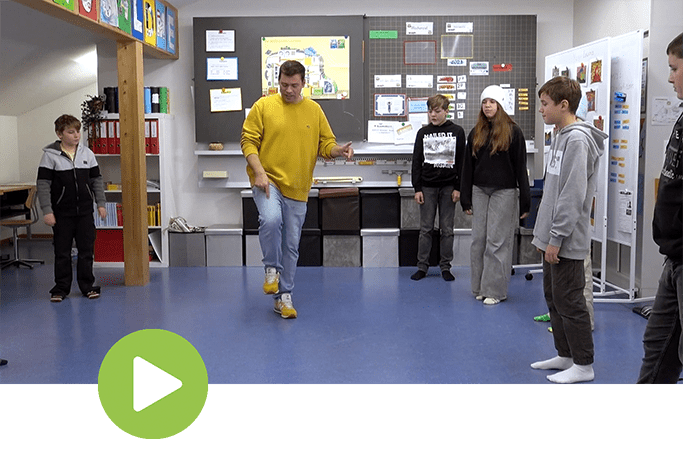 Ein Lehrer zeigt den Schülern die Beinarbeit des Atlanta Stomp Tanzschritts – groove2grow MOVES Tutorial.