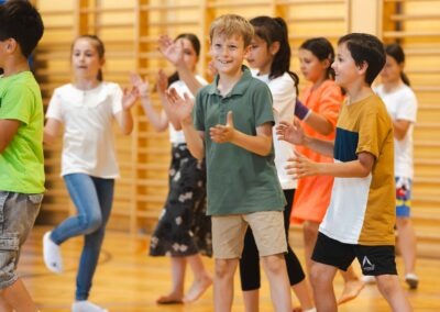Lachende Schüler beim gemeinsamen Tanzen und Klatschen im Rahmen des groove2grow Projekts in Wels.