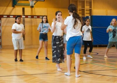 Zwei lachende Schülerinnen klatschen sich während einer Tanzpause in der Turnhalle ab – Ausdruck von Freude, Gemeinschaft und Erfolg.
