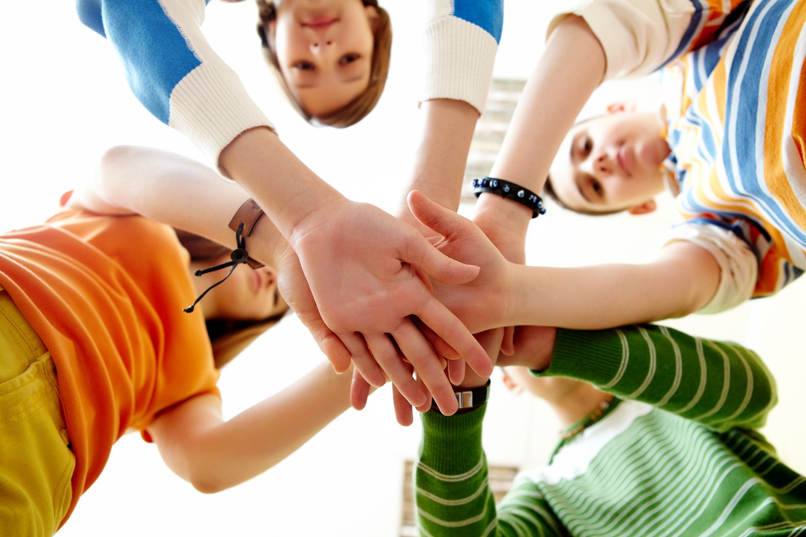 Eine Gruppe von Kindern legt im Kreis die Hände aufeinander – Symbol für Klassengemeinschaft und Teamarbeit durch Tanz.
