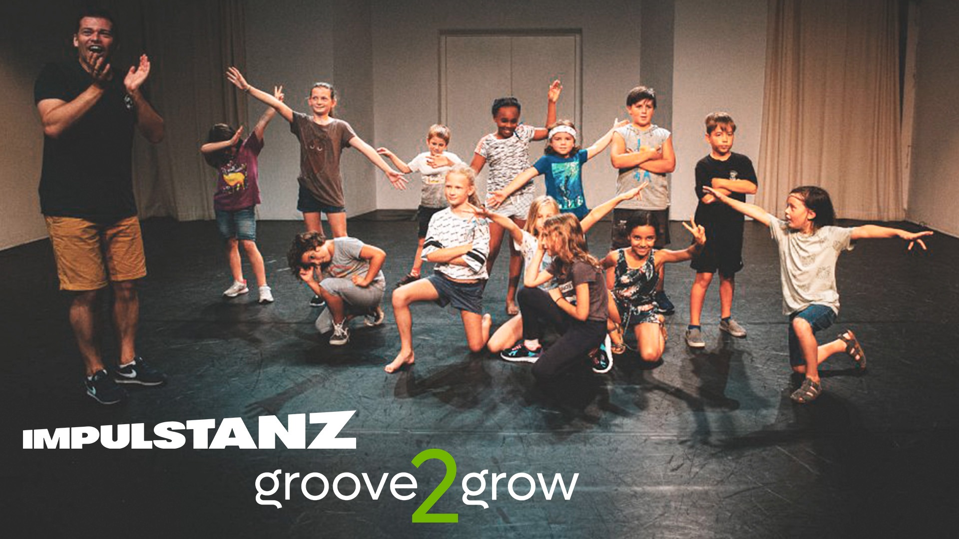 Eine Gruppe von Kindern posiert gut gelaunt in coolen HipHop- und Breaking-Posen auf einer Bühne im Dschungel 2 während eines ImPulsTanz Workshops von groove2grow.