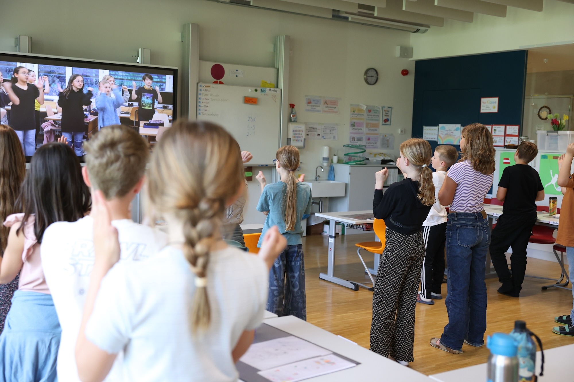 Wo Unsicherheit endet: Digitale Unterstützung für den Tanzunterricht Schüler*innen folgen in einem Klassenzimmer einem digitalen Tanzvideo auf einem großen Bildschirm – moderne Tanzvermittlung mit groove2grow.