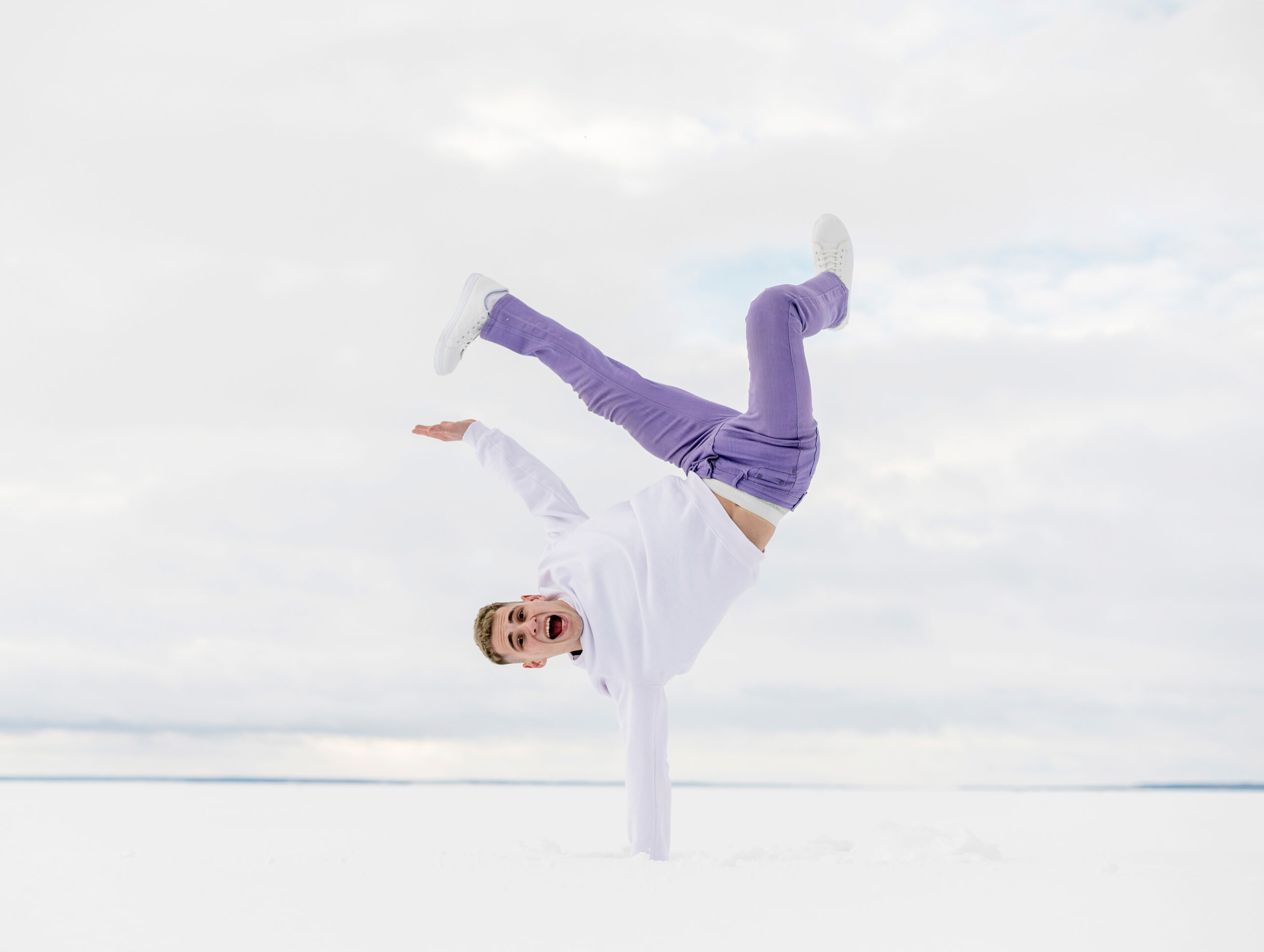 Nonverbaler Ausdruck: Wenn der Körper spricht Ein junger Mann vollführt einen einhändigen Handstand im Schnee und schreit vor Freude – Ausdruck von Emotionen durch Tanz.