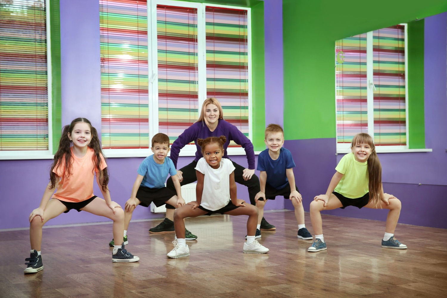 Soziale Wirkung von Tanz im Schulunterricht | groove2grow Eine Gruppe von Schulkindern tanzt gemeinsam mit einer Lehrerin in einem bunten Tanzstudio und trainiert rhythmische Koordination im groove2grow Unterricht.