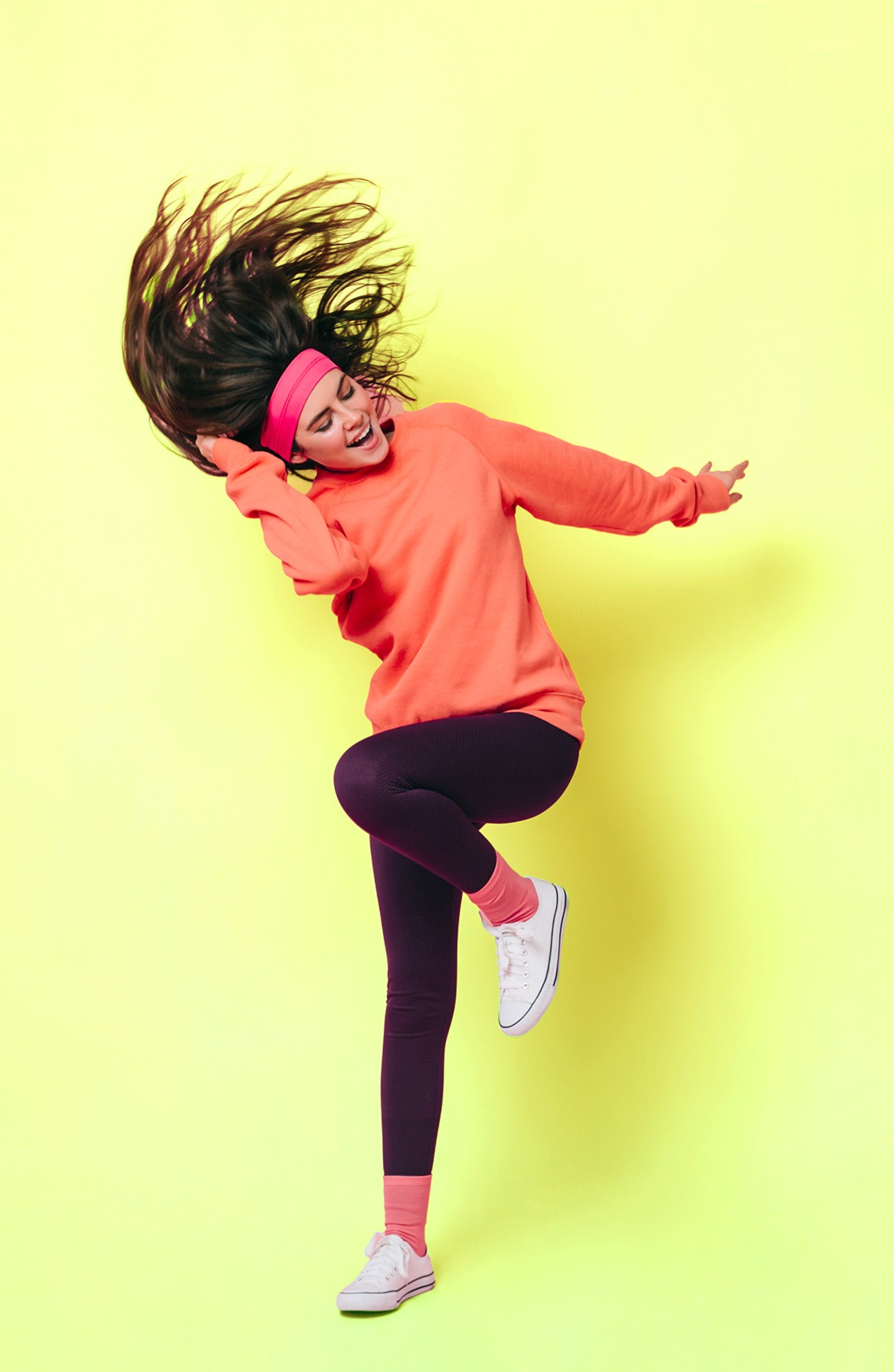 Kulturelle Vielfalt entdecken mit groove2grow Eine junge Frau tanzt energiegeladen vor gelbem Hintergrund – Symbol für die kulturelle Vielfalt im Tanz.