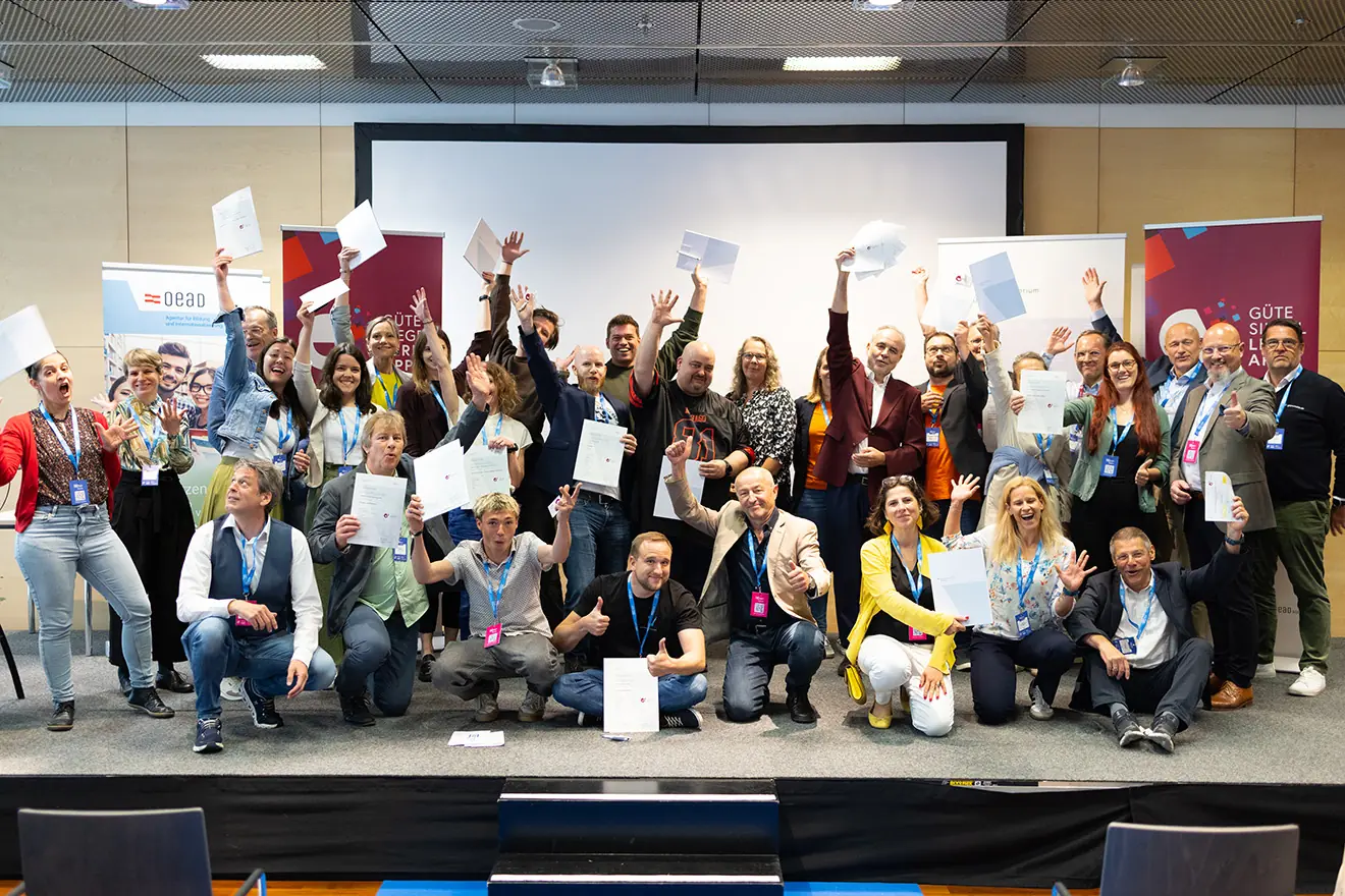 Ein Gruppenfoto zahlreicher Preisträger auf einer Bühne, die stolz ihre Zertifikate für das Gütesiegel Lern-Apps 2025 in die Kamera halten.