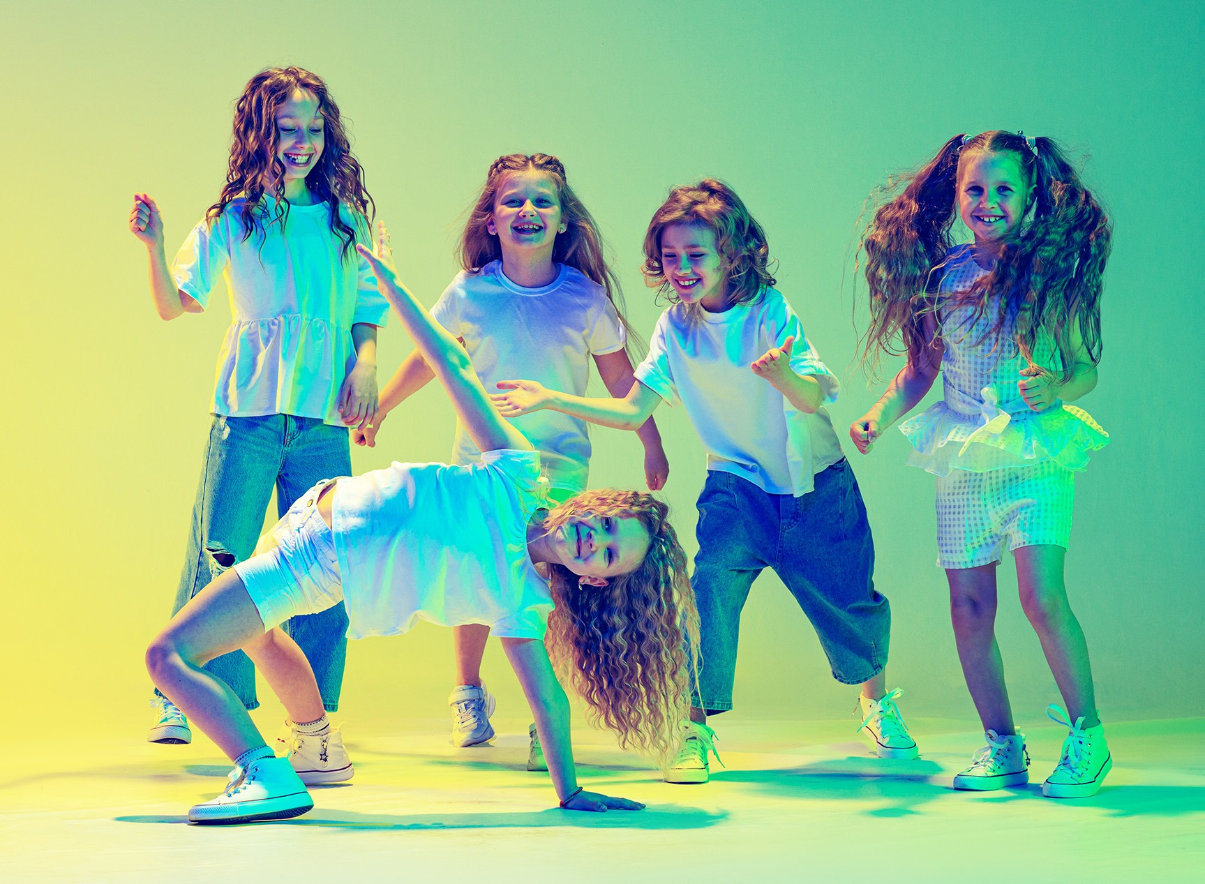 Fünf Kinder tanzen kreativ und individuell unter buntem Licht – Förderung der persönlichen Ausdrucksfähigkeit.