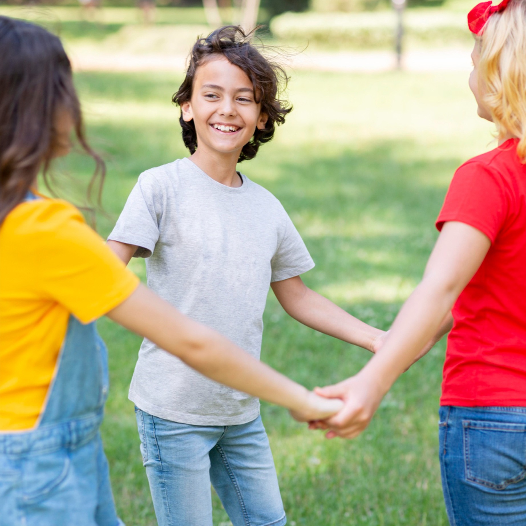 Lachende Kinder halten sich im Kreis an den Händen und symbolisieren die Freude an gemeinsamer Bewegung im Freien.