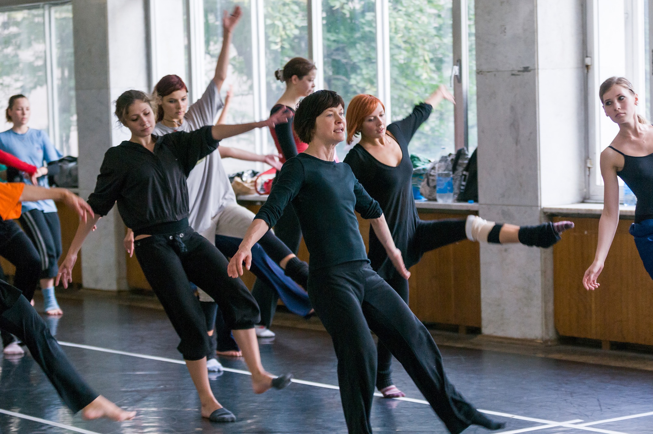 Praxisnahe Fortbildungen für Kollegien Eine Gruppe von Pädagoginnen praktiziert aktiv moderne Tanz- und Bewegungsabläufe in einem hellen Tanzstudio während einer groove2grow Fortbildung.