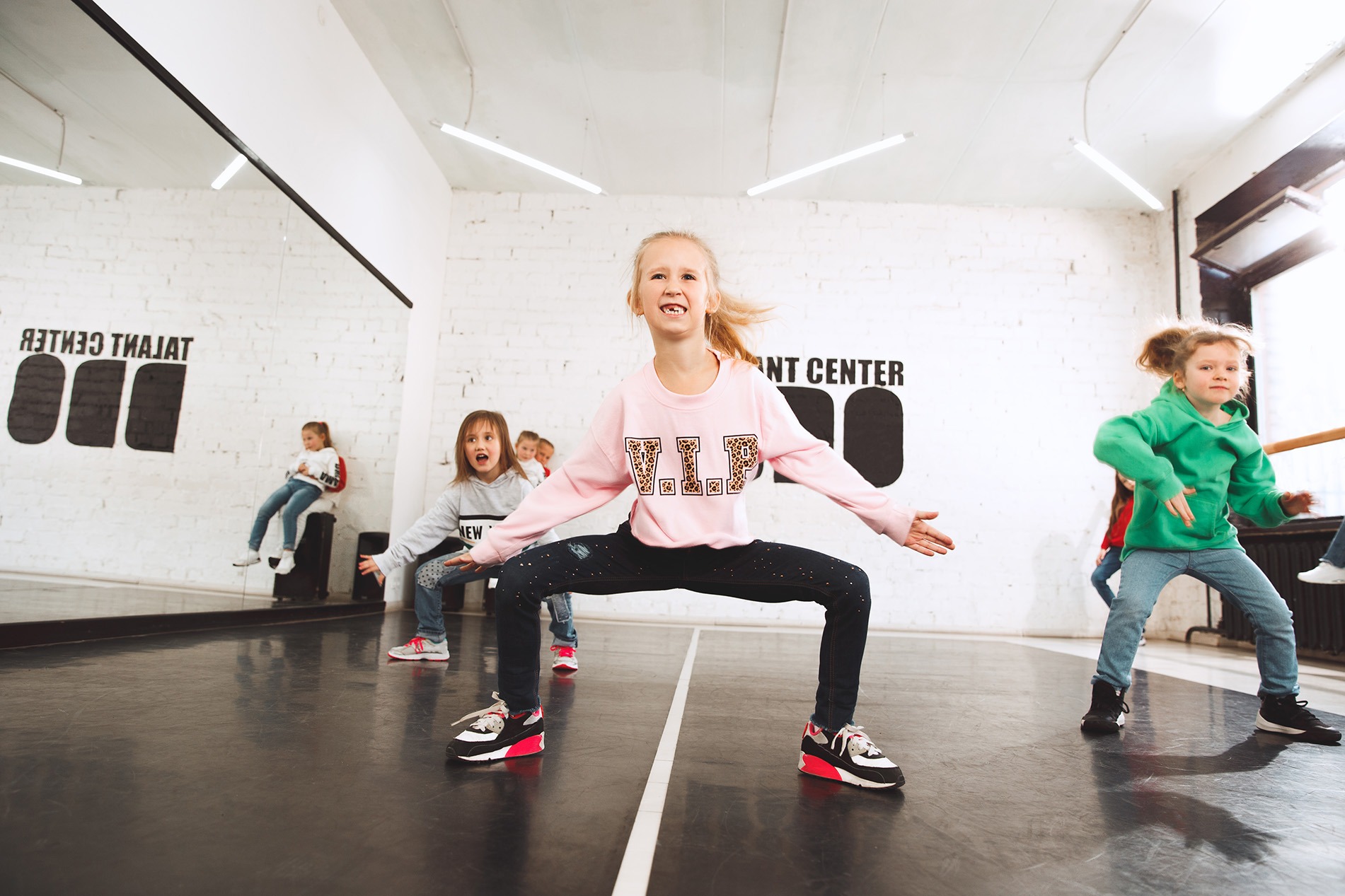 Eine Gruppe von Schülerinnen tanzt begeistert und voller Energie in einem modernen Tanzstudio während eines groove2grow Workshops.